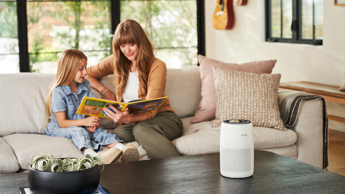 Mom and daughter reading on couch with air purifier nearby