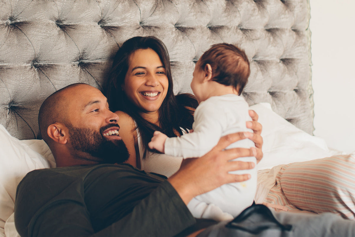 Mom and dad lay in bed and hold newborn baby