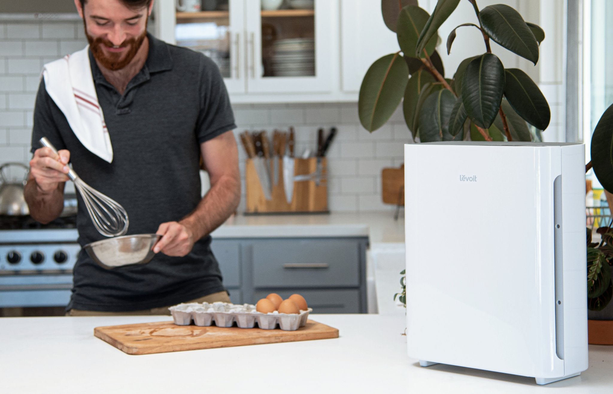 Levoit air purifier in a kitchen setting, with a person whisking ingredients, showing the appliance's effectiveness in maintaining clean air.