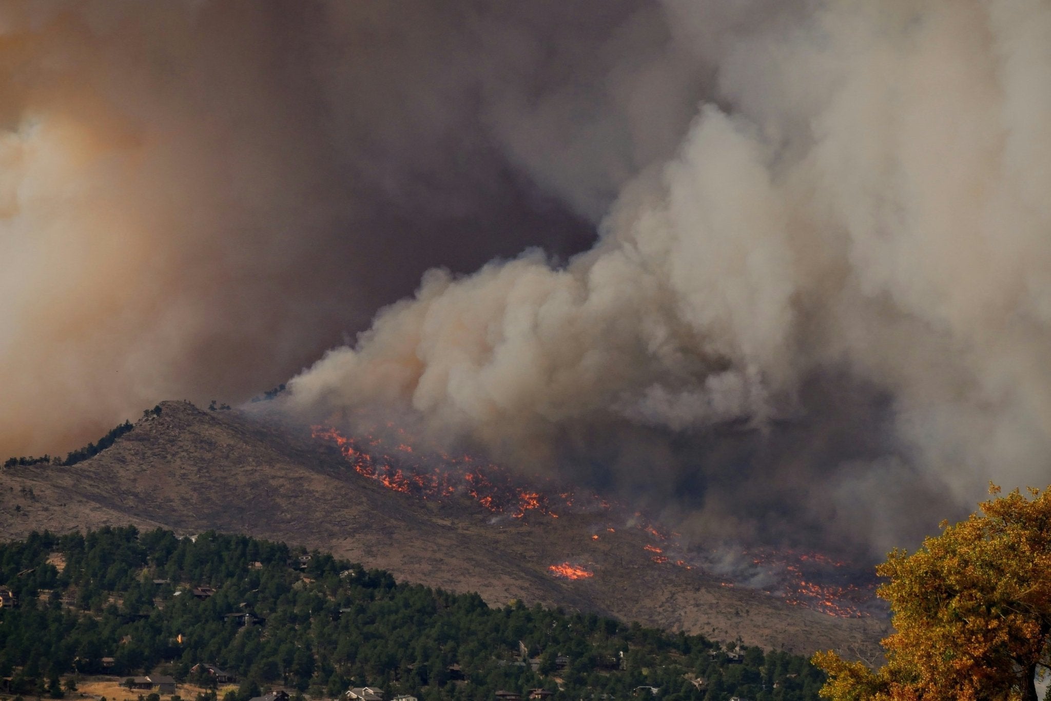 Wildfire on mountain and plume of smoke in the air above it