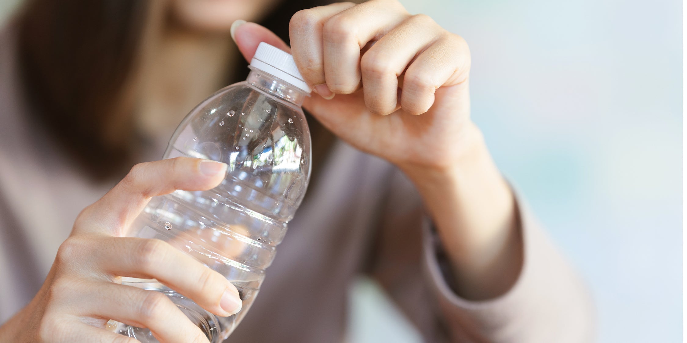 Women opening lid on plastic single use water bottle