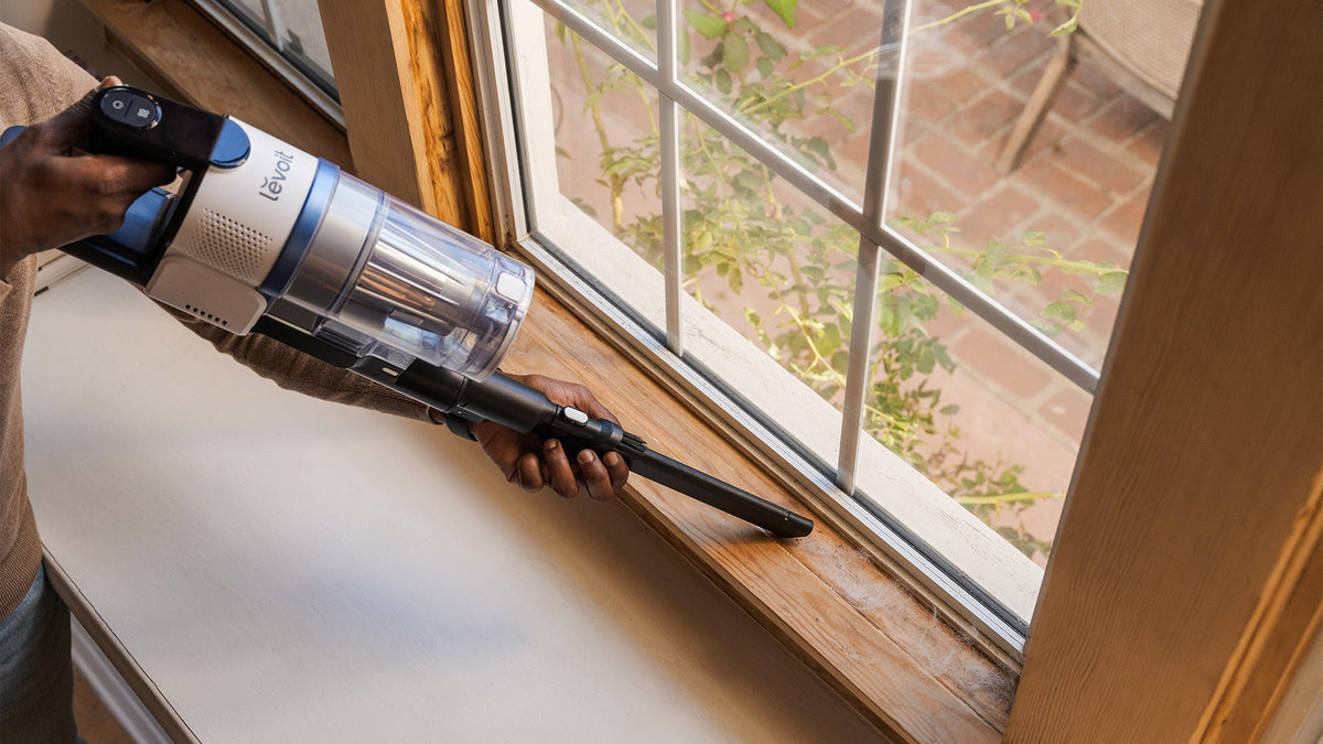 Handheld vacuum cleaning dust on windowsill